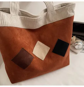 Brown corduroy tote bag detail showing geometric color-blocked square patches and sturdy handles.