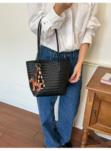 Detailed view of the black woven leather shoulder tote bag with a cute puppy bag charm.