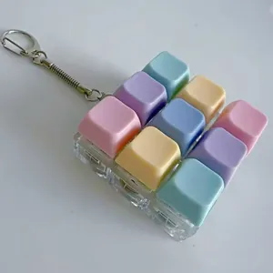 Porte-clés fidget jouet à touches mécaniques pastel colorées avec une base transparente.