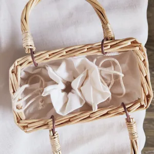 Chic borsa a mano in rattan intrecciato con sacchetto interno con coulisse bianca, vista dall'alto.