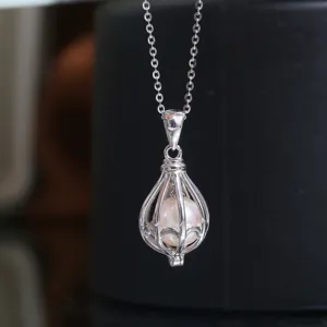 Gros plan détail d'un pendentif lanterne cage en argent avec perle. Beau bijou délicat.