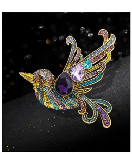 Primo piano dei dettagli della spilla colibrì in strass colorati, pietre di vetro e metallo.