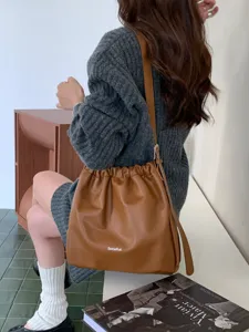 Detailed view of the brown slouchy bucket bag, featuring chic drawstring ruching and soft faux leather.