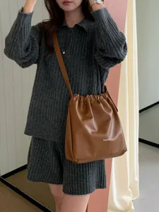 Detailed view of brown faux leather crossbody bucket bag with elegant drawstring design.