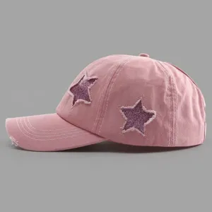 Detailed view of pink vintage washed distressed baseball cap with glitter star patches.