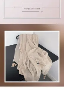 Close-up view of a minimalist pleated beige scarf with delicate tassels for daily fashion wear.