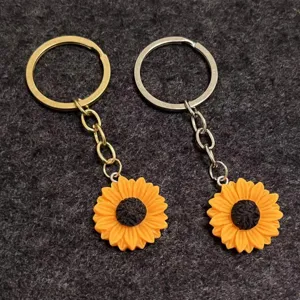 Nahaufnahme von zwei Harz Sonnenblumen Schlüsselanhängern mit goldenen und silbernen Ringen.
