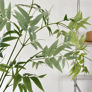 Artificial green bamboo leaf single branch, indoor Zen tea room plant decor detail.