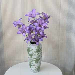 Detail view of purple artificial lily flower bouquet in a green splatter ceramic vase.
