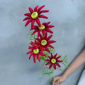 Nahaufnahme Detail des roten künstlichen Blumenastes mit lebendigen Blüten und grünen Blättern.
