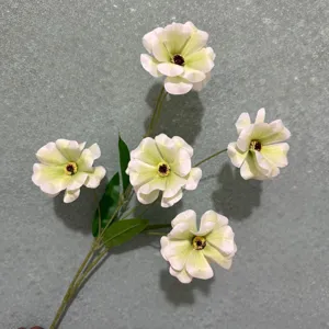 Primo piano di ranuncoli artificiali che mostrano delicati petali bianchi e foglie verdi.