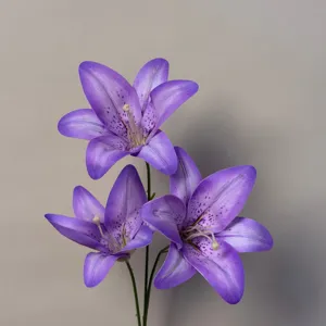Detail shot of purple artificial lily flowers showing petal spots and green stems.