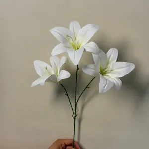 Closeup detail of artificial white lily flower branch, realistic petals and stem texture.