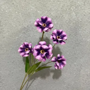 Primo piano dettagliato di teste di fiori di ranuncolo viola artificiali con foglie verdi casa.