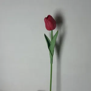 Detaillierte Nahaufnahme einer künstlichen roten Tulpe mit realistischem grünem Stiel und Blättern.