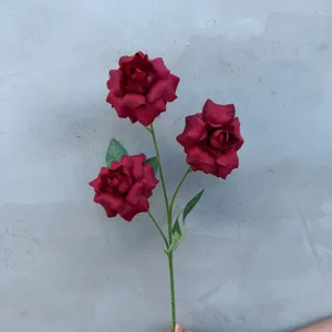 Detailaufnahme von künstlichen roten Rosen mit drei Blüten und grünen Blättern für Dekor.