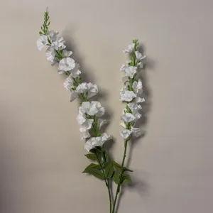 Vista dettagliata dei gambi di fiori artificiali bianchi, con petali delicati e foglie verdi.