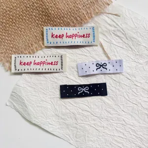 Embroidered fabric clothing labels with cute bow and letter designs for DIY craft decoration.