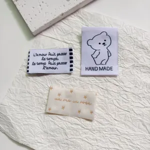 Detailed view of DIY embroidered fabric labels with cute bear and French quotes for clothes.