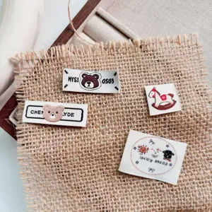 Details of cute woven labels for clothing, featuring embroidered bear, rocking horse and sheep designs.