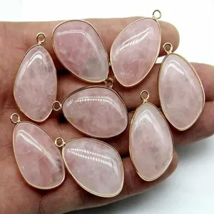 Detailed closeup of natural rose quartz teardrop pendants with gold plated edge for DIY jewelry.