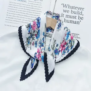 Pleated floral scarf detail, elegant white neckerchief with blue pink flowers and black trim.