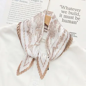 Detail shot of pleated white scarf with brown print, delicate texture and elegant decorative look.