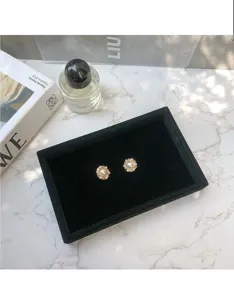 Vue detaillee d'un petit plateau de presentation de bijoux en velours noir sur marbre.