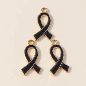 Detail shot of black enamel ribbon alloy charms, gold trim bow pendants for DIY jewelry making.