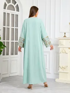 Scopri questo elegante abito caftano verde chiaro con polsini ricamati di paillettes.