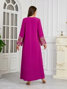 Vista posteriore di un lungo abito caftano fucsia con eleganti polsini ricamati d'oro.
