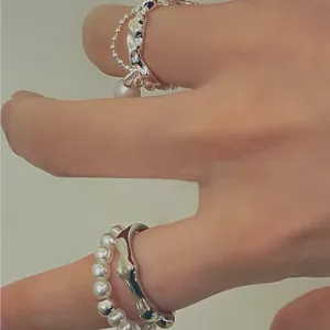 Nahaufnahme von unregelmäßigen Metall- und Perlenringen, süßer cooler Schmuckdetail.