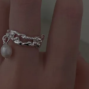 Nahaufnahme Detail eines unregelmäßigen silbernen Ringes mit Perlenanhänger am Finger.