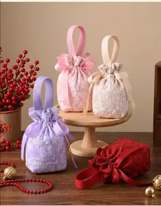 Detail shot of fabric candy gift bags with floral embossing, bows and ribbon handles on wooden stand.