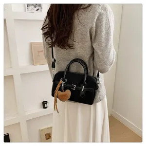 Gedetailleerd overzicht van de retro suède Boston handtas met een mooi hart-hangertje.