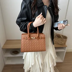 Braune Leder Handtasche mit Bambusblattmuster und Metallschloss in eleganter Trageansicht.