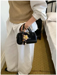 Black Boston handbag detailed view showcasing exquisite straw flower charm and elegant design.