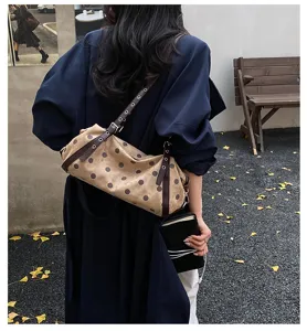 Detail shot of a Korean-style polka dot shoulder bag with brown straps, outdoor view.