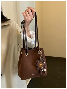 Retro brown suede bucket bag with stylish flower charm and double handles for women daily commute.