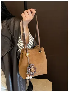Retro brown bucket bag for women, stylish PU leather shoulder bag with floral charm pendant.