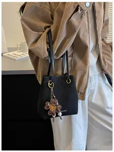 Detail view of black fashion bucket bag with flower charm, vintage style chic daily shoulder bag.