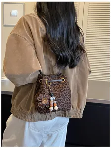 Detail view of the brown leopard print bucket bag worn on shoulder with floral charm.