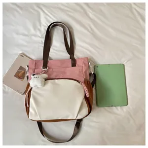 Vue détaillée du sac bandoulière en toile tendance pour étudiant avec sangle et pendentif en peluche.