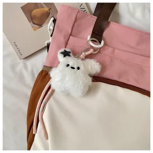 Gros plan detaille du sac cabas en toile rose avec charmant porte-cles en peluche doux.