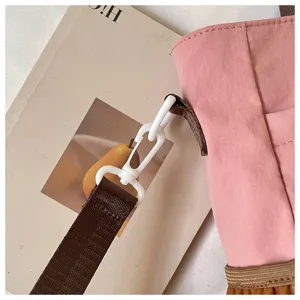 Gros plan sur la sangle du cartable rose et la boucle en plastique blanc élégant.