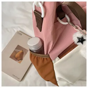 Vue détaillée du sac bandoulière étudiant rose et blanc avec poche latérale et pendentif étoile