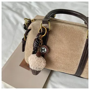 Retro brown suede handbag detail shot, showing delicate texture and cute plush keychain.
