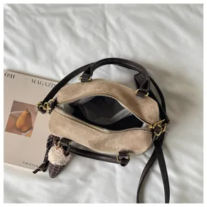 Close-up detail of the vintage suede crossbody bag showing zipper opening and cute charm.