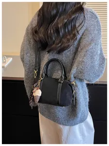 Black suede crossbody handbag with top handles and cute ice cream charm for autumn fashion.