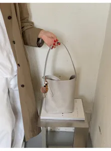 Sac seau tissé gris minimaliste pour femme, sac porté épaule polyvalent avec charm perle chic.